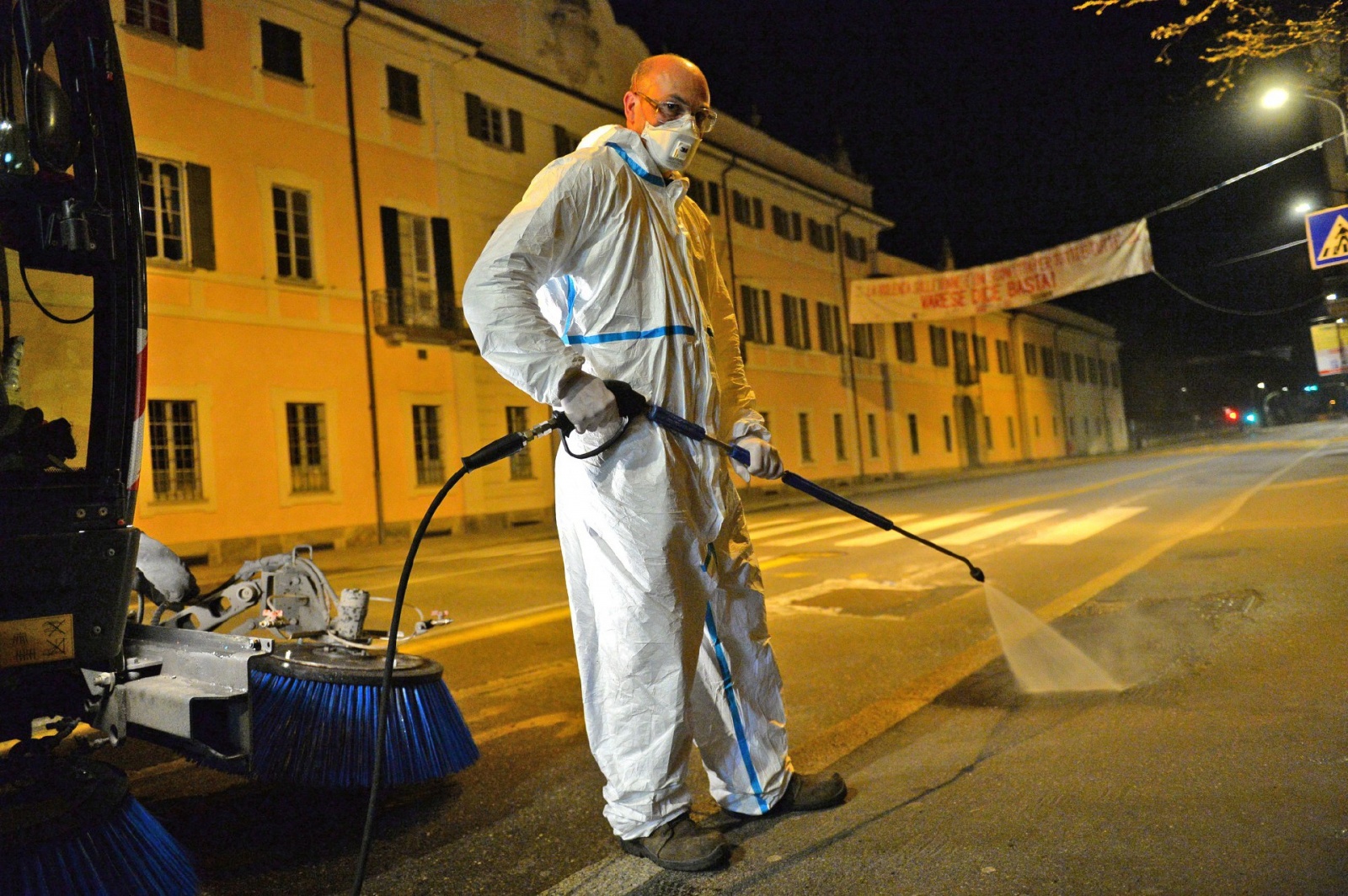VARESE OPERATORI ASPEM IN TUTA, OCCHIALI E MASCHERINA, LAVANO STRADE E MARCIAPIEDI CON LANCIA E SPAZZATRICE, PER CORONAVIRUS