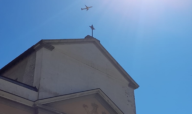 Un aereo passa sopra la chiesa di Santa Maria Assunta