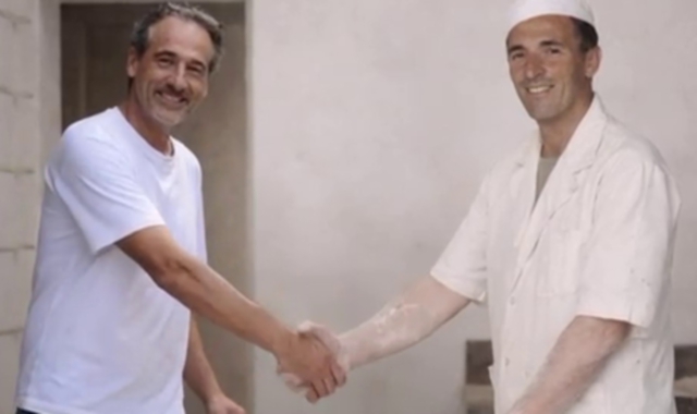 Un immaginario passaggio del testimone per il dialetto col nonno fornaio  (foto AI)